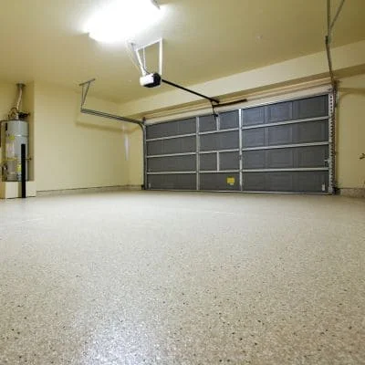 Dark gray sectional garage door with overhead opener system in residential garage