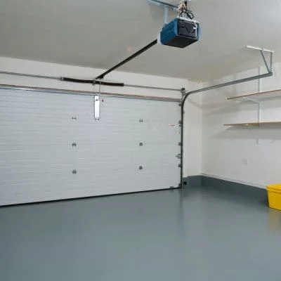 White sectional garage door with blue automatic opener and epoxy floor coating