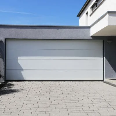 White sectional garage door with horizontal panels on modern home with paved driveway