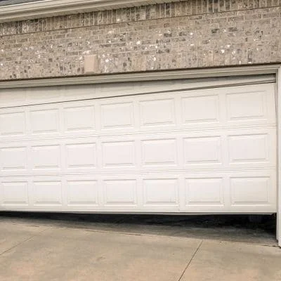 White raised-panel garage door with horizontal sections on brick home exterior