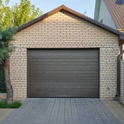Gray sectional garage door on brick garage with gray paver driveway